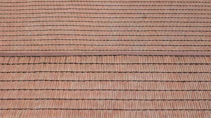 Vista aerea di un tetto formato da tegole rosse ordinate ma anche rovinate dal tempo.