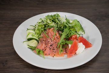 Meat of trout on a plate with vegetables and grapefruit