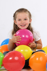 Fototapeta na wymiar Kleines Mädchen mit Kinn auf einem Luftballon sitzt zwischen Ballons