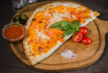 Hot piece of pizza with melted cheese on a rustic wooden table