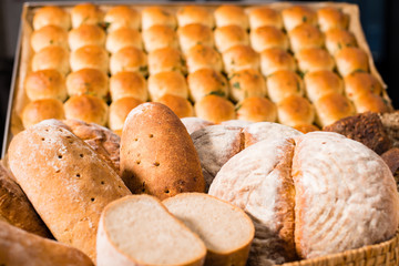 on the foreground various types of fresh bread. And on the background buns set. Rustic style