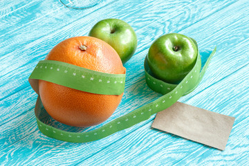 Mockup of business card. Grapefruit and green apple on wooden turquoise table with tape measure. Healthy food and diet concept. Flat lay.
