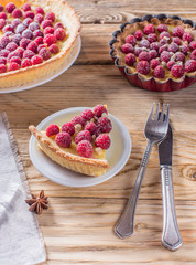 Sweet tart with raspberries, and nuts, powdered sugar on dark stone background.