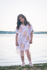 Portrait of little fashionable girl walking on berth near sea