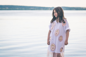 Portrait of little fashionable girl walking on berth near sea