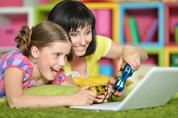 Obraz premium mother and daughter playing game on laptop
