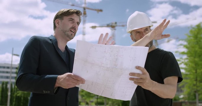 Attractive architect and construction manager discussing constructions plans outside