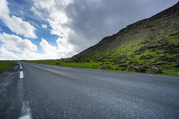 Iceland - Green mountain behind highway with car