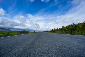 Fototapeta premium Iceland - Empty highway between green plants and mountains