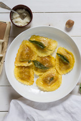 Grilled vegetables ravioli with sage butter. White wooden table, white plate.