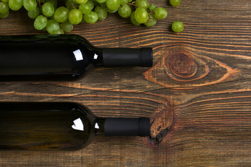 Obraz premium Bottles of wine and ripe grapes on wooden background