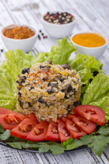 Rice with mushrooms and green lettuce leaves on rustic table background
