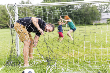 Cheerful family playing football in a park