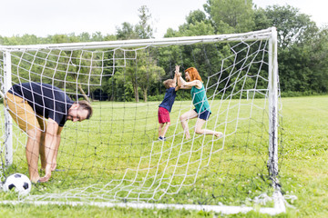 Cheerful family playing football in a park