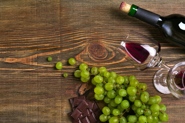 Two glasses, bottle of red wine and grape on a wooden table