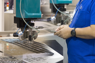 The technician operator using the smart phone  for control  the water jet machine.hi-precision...