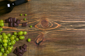 Fototapeta na wymiar Bottle of wine and ripe grapes on wooden background