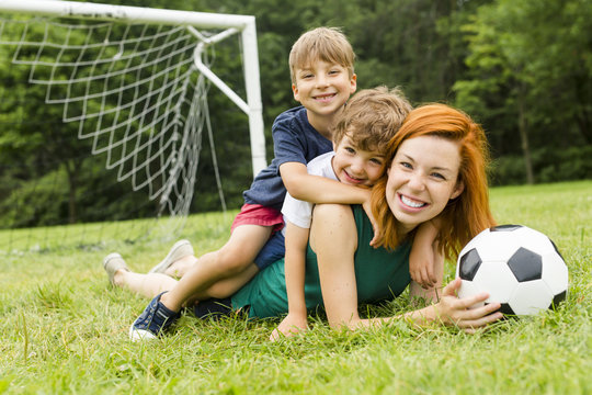 Image of family, mother and son playing ball in the park