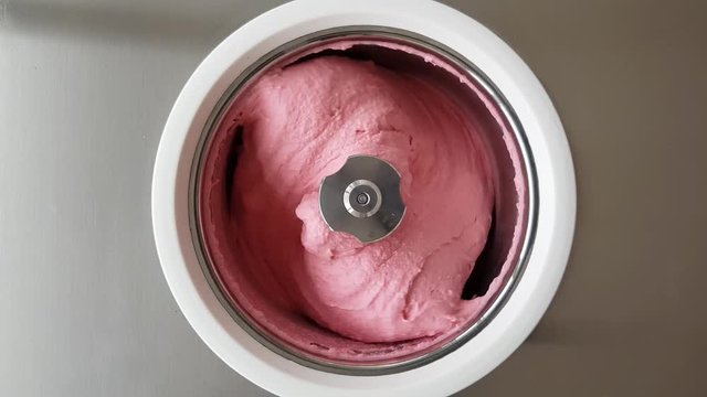 Homemade raspberry ice cream churning in a small professional  ice cream machine. 