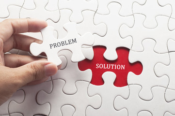 Hand holding piece of jigsaw puzzle with word problem & solution. - obrazy, fototapety, plakaty