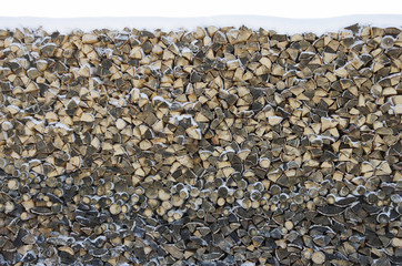 Birch firewood stacked in a woodpile covered with snow
