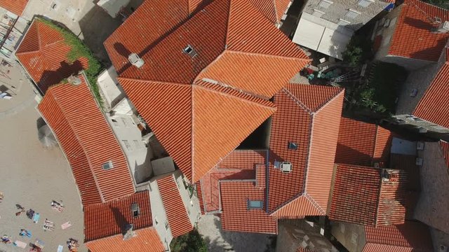 Take off and rising above Budva Montenegro old town with red tile rooftops. Aerial footage.