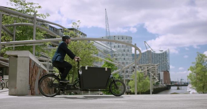 Handsome man is riding with his cargo bike through the city