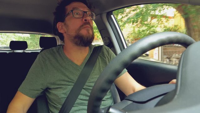Happy man dancing and singing like crazy while driving car in city