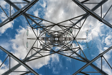 under a high voltage pylon on blue cloudy sky background