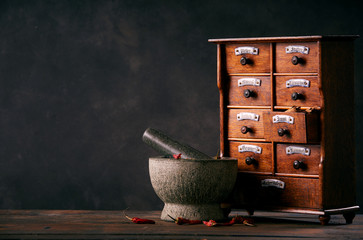 Mortar with pestle standing by spice drawers