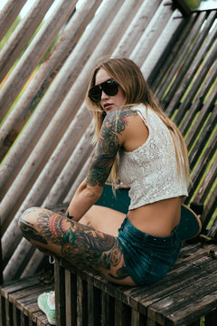 Young tattooed girl skate boarding around town.