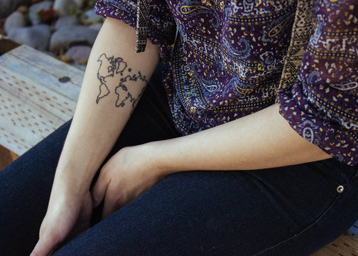 a young woman's hands in her lap with a tattoo on her forearm