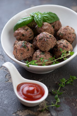 White bowl with baked meatballs and sauce, selective focus, close-up