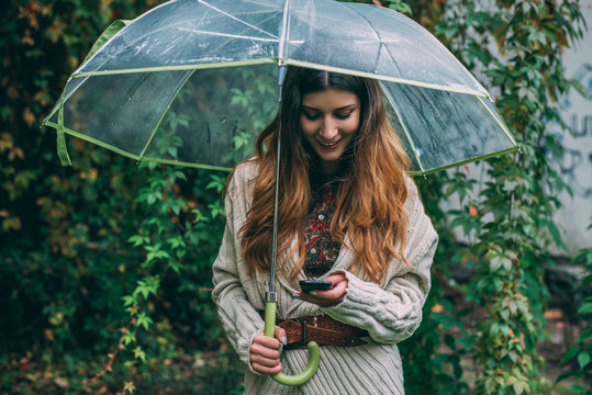 Woman holding umbrella and looking at the phone