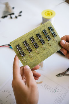 Technology: young man manually assembling printed circuit board