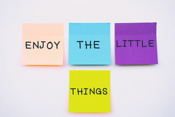 Enjoy the little things - Inspirational and motivation quotes on colorful sticky paper on a wall, pastel colors.