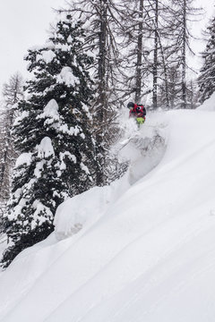 young male freerider skiing down a powder slope