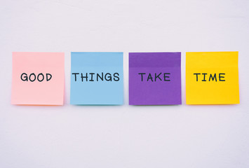 Good things take time - Inspirational and motivation quotes on colorful sticky paper on a wall, pastel colors.