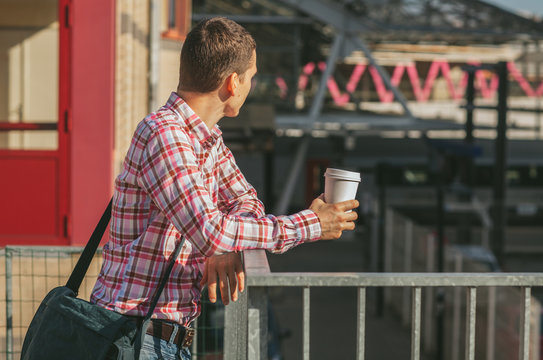 Man Standing on the Street and Holding Coffee
