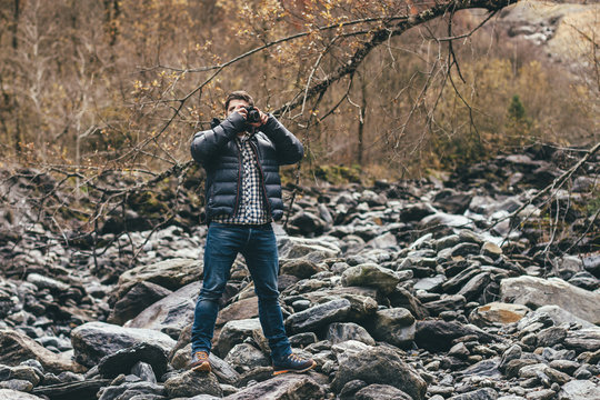 young man taking photo in autumnal rocky landscape