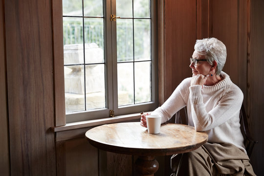 Mature woman relaxing with tea by window