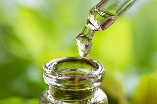 A drop of essential oil is being dropped into a bottle