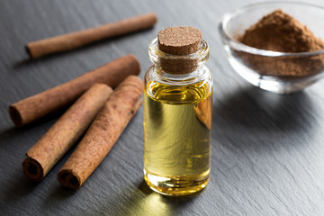 A bottle of cinnamon essential oil with cinnamon sticks