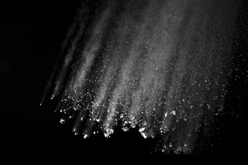 Freeze motion of white dust explosion on black background. Stopping the movement of white powder on dark background. Explosive powder white on black background.