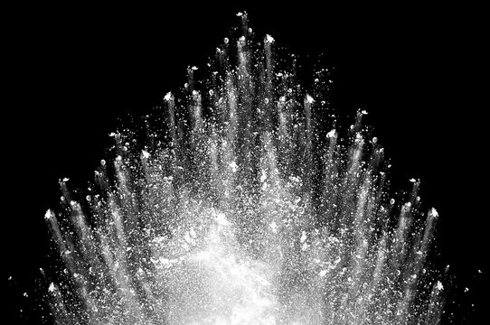 Freeze motion of white dust explosion on black background. Stopping the movement of white powder on dark background. Explosive powder white on black background.