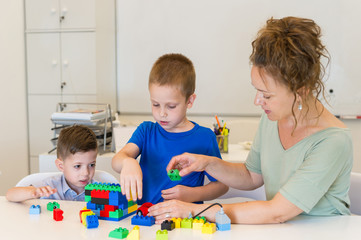 Obraz premium teacher woman play with two child boy with cubes in the kindergarten
