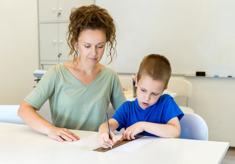 teacher woman learn to use ruler to preschooler boy in the classroom
