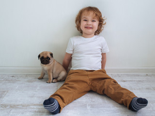 Little cute redhead curly boy in white t-shirt  with his pug puppy © polya_olya