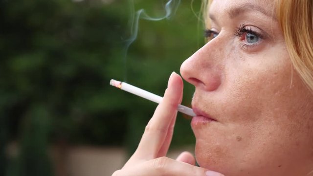 A woman smokes in the summer on the street thin cigarettes. 4 . Slow-motion