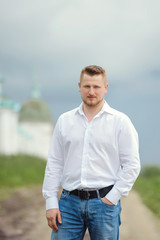 Portrait of man in white shirt with hand in pocket looking at camera